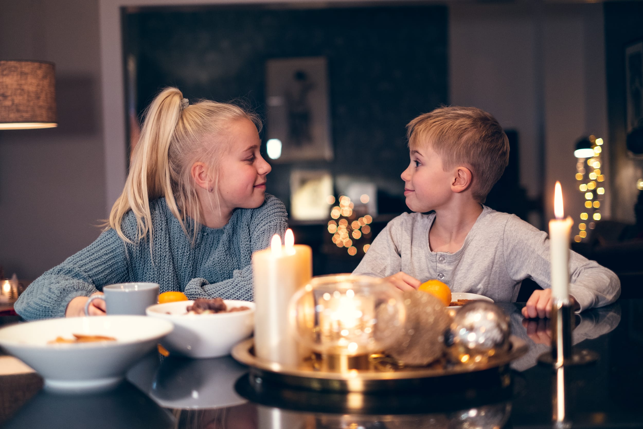 Søsken sitter sammen foran julepyntet bord.