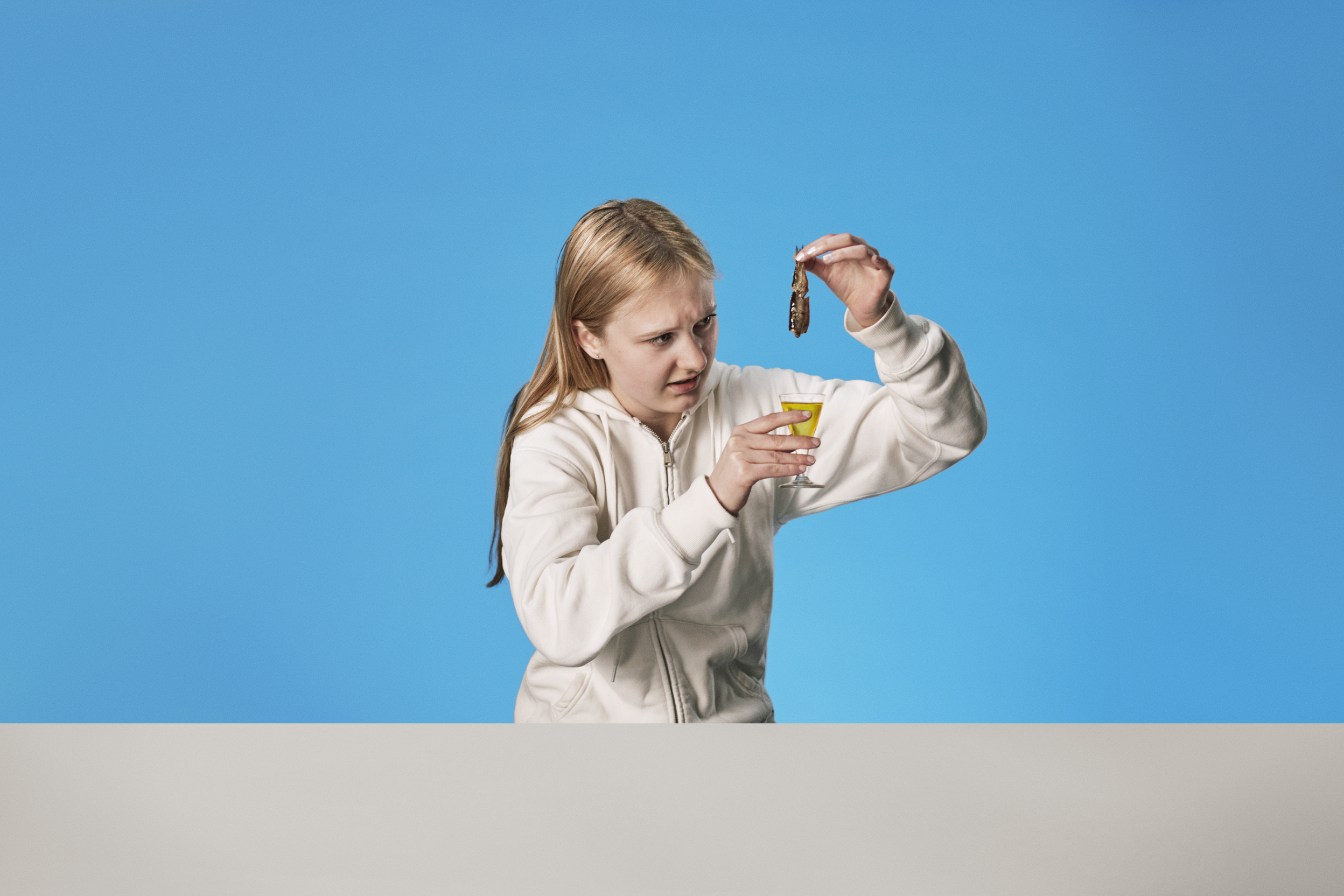 Student med hvit hettegenser smaker på fiskeoljeshot