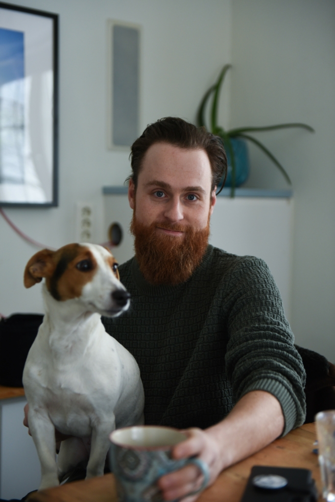 Per Arthur Andersen poserer mens han holder en kaffekopp og har en hund på fanget