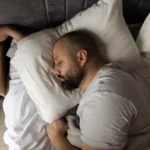 man sover i seng men hånden under puta
