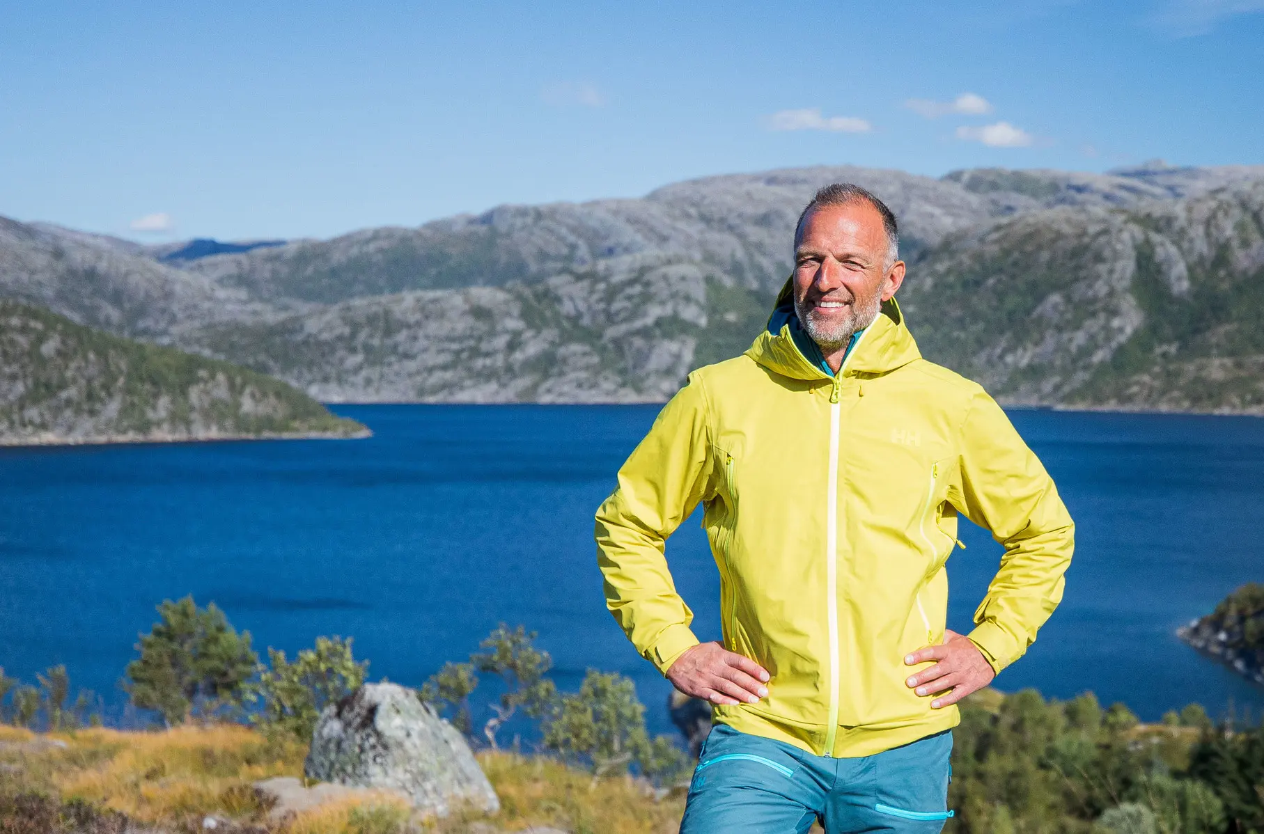 Tom Stiansen poserer foran kamera i naturen med grønn jakke