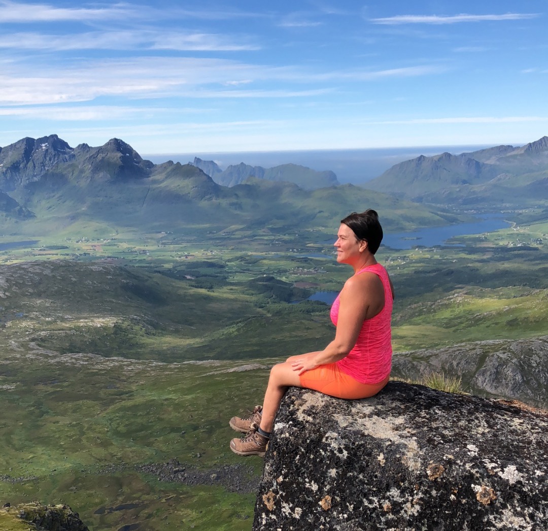 Wenche sitter på en fjelltopp og nyter utsikten