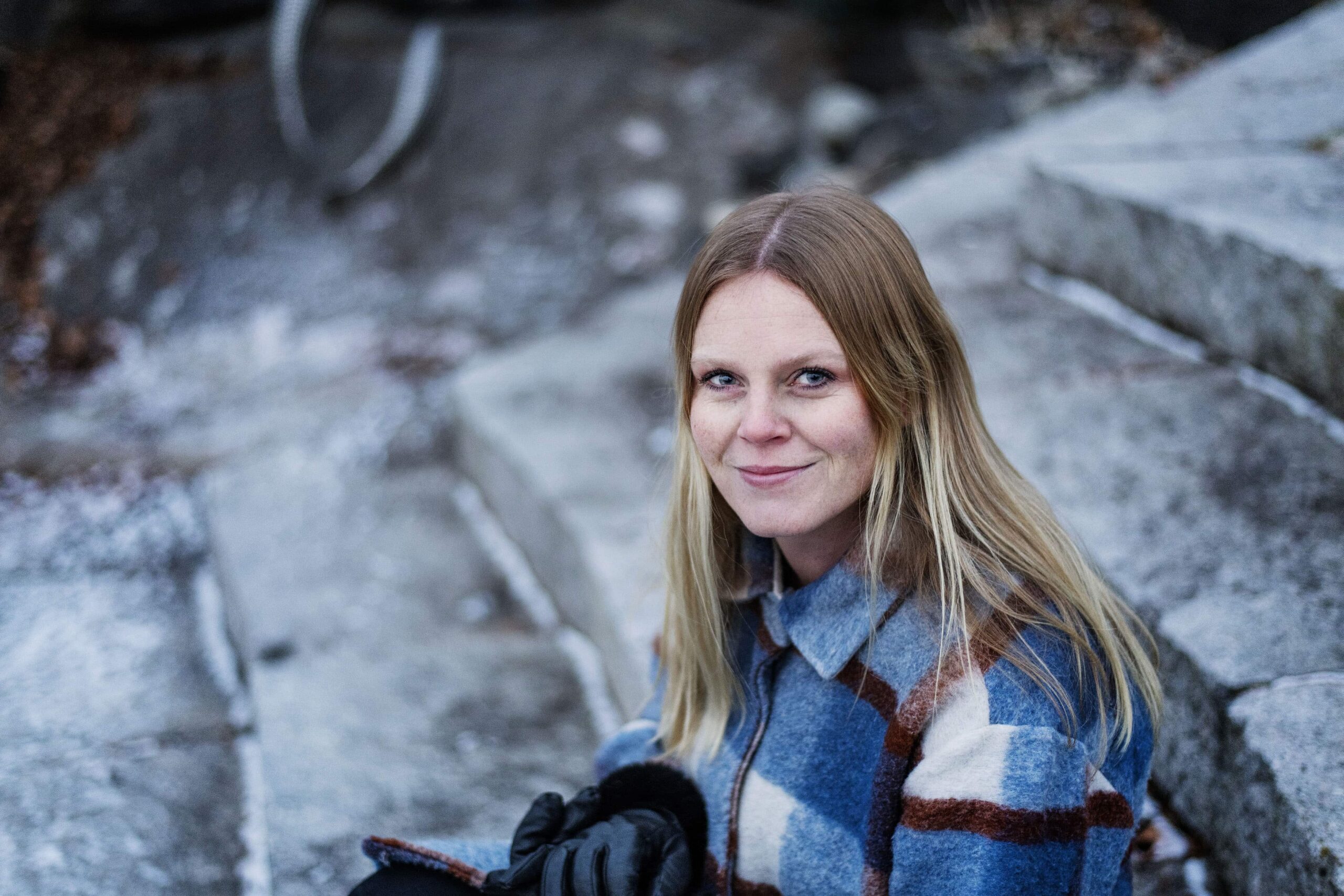 Aasne Sørumshaugen som ser opp mot kamera og smiler. 
Hun har på seg en stripet jakke. 