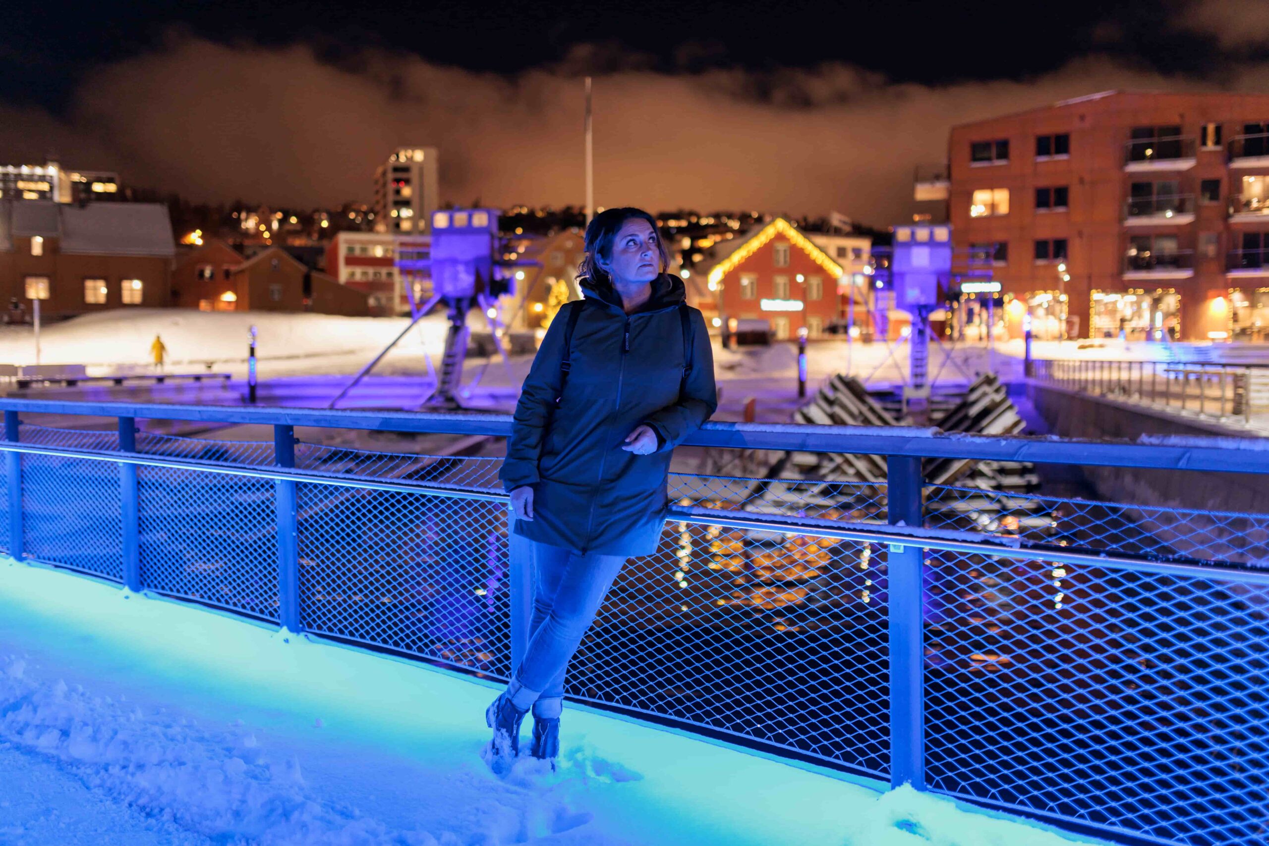 Christel på en bro i Trondheim. Hun lener seg mot rekkverket. 