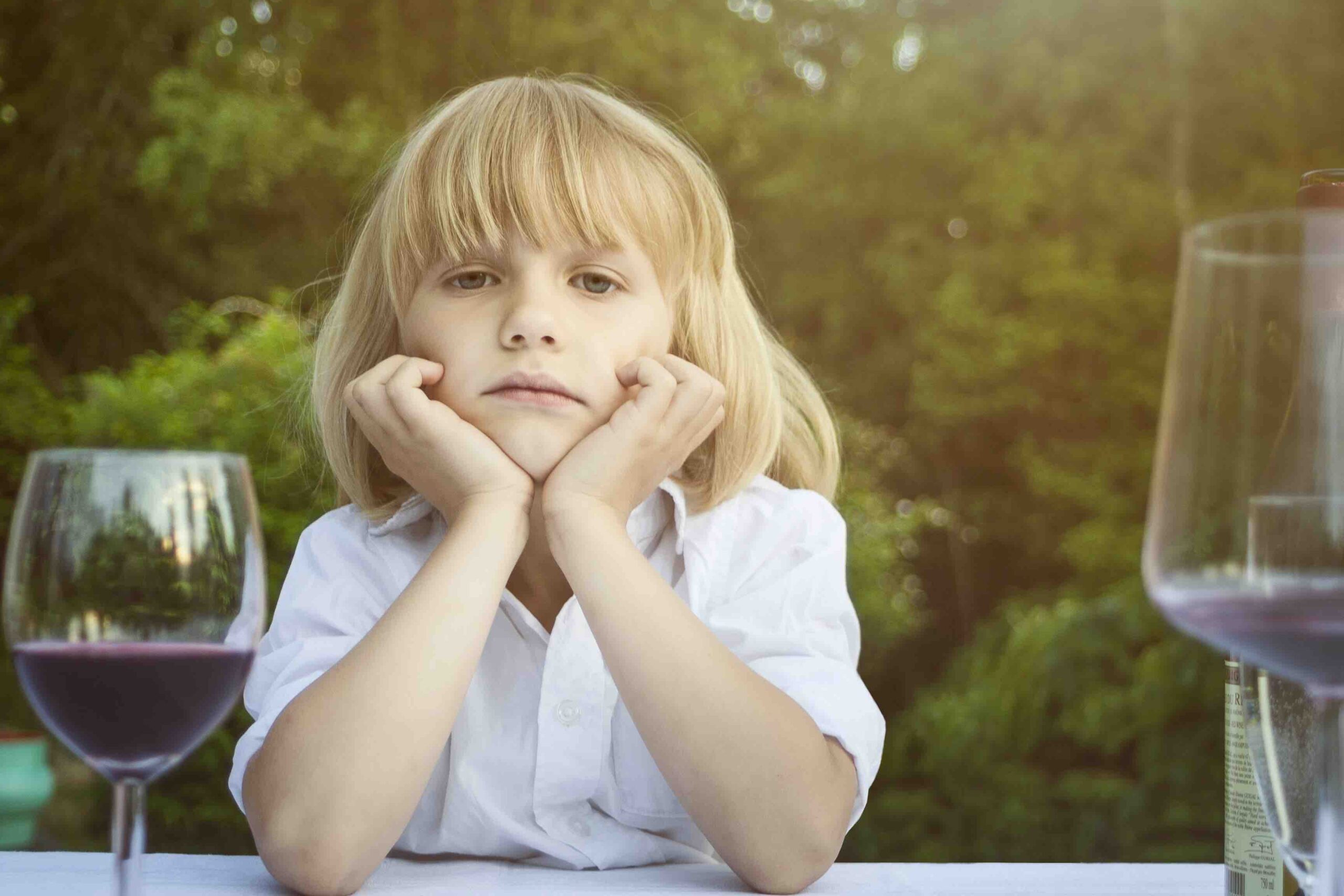 Lukas (6) ser inn i kameraet. Ved siden av han er noen vinglass.