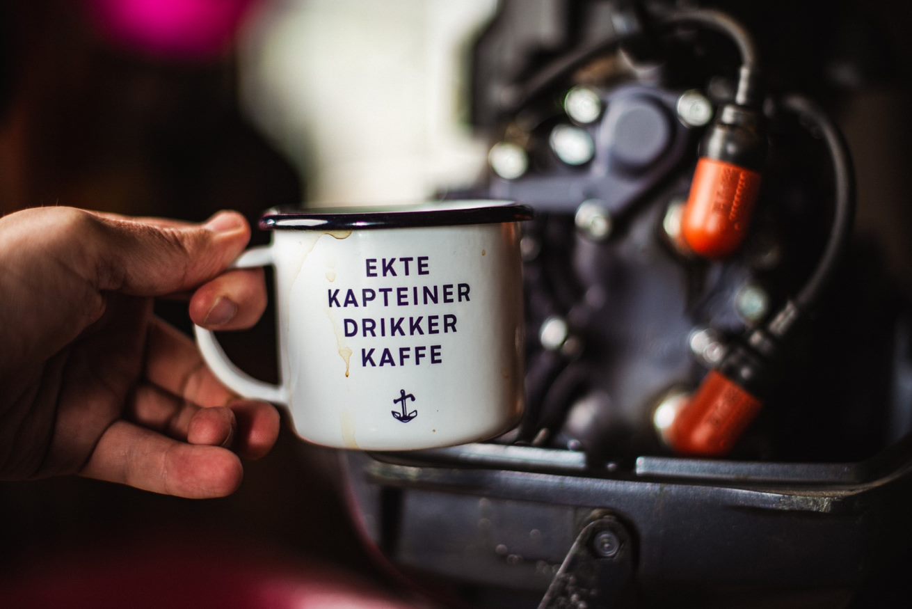 Bilde av en hånd som holder en kaffekopp med påskriften "ekte kapteiner drikker kaffe".