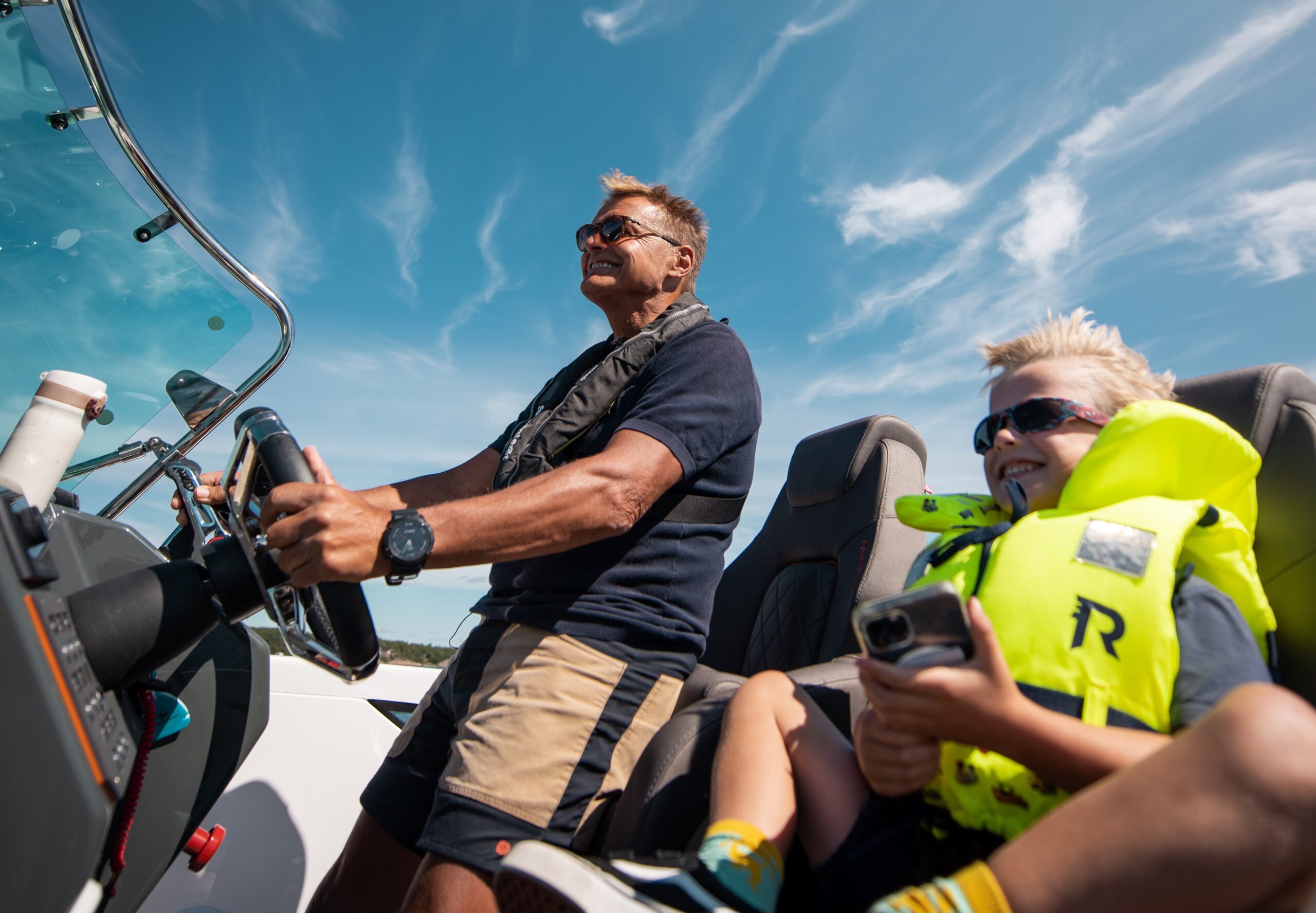 Dag Otto kjører båt med sitt barnebarn en solfylt sommerdag