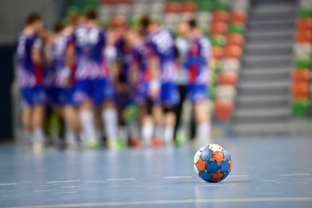 Bilde av en håndball med et lag i bakgrunnen ute av fokus