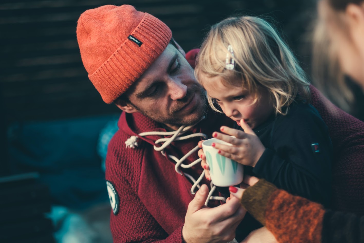 En pappa hjelper den lille datteren sin med å drikke fra en kopp.