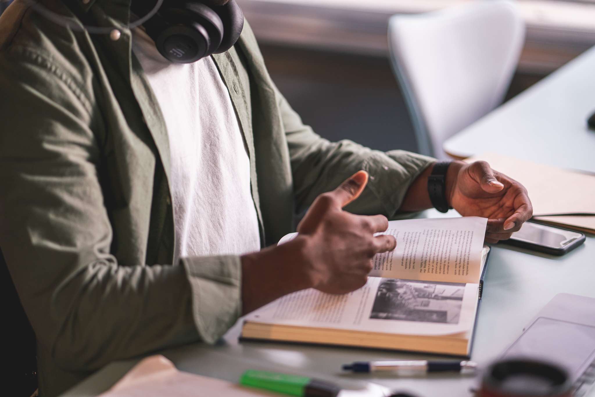 person sitter og leser bok, fokus på hendene og boka