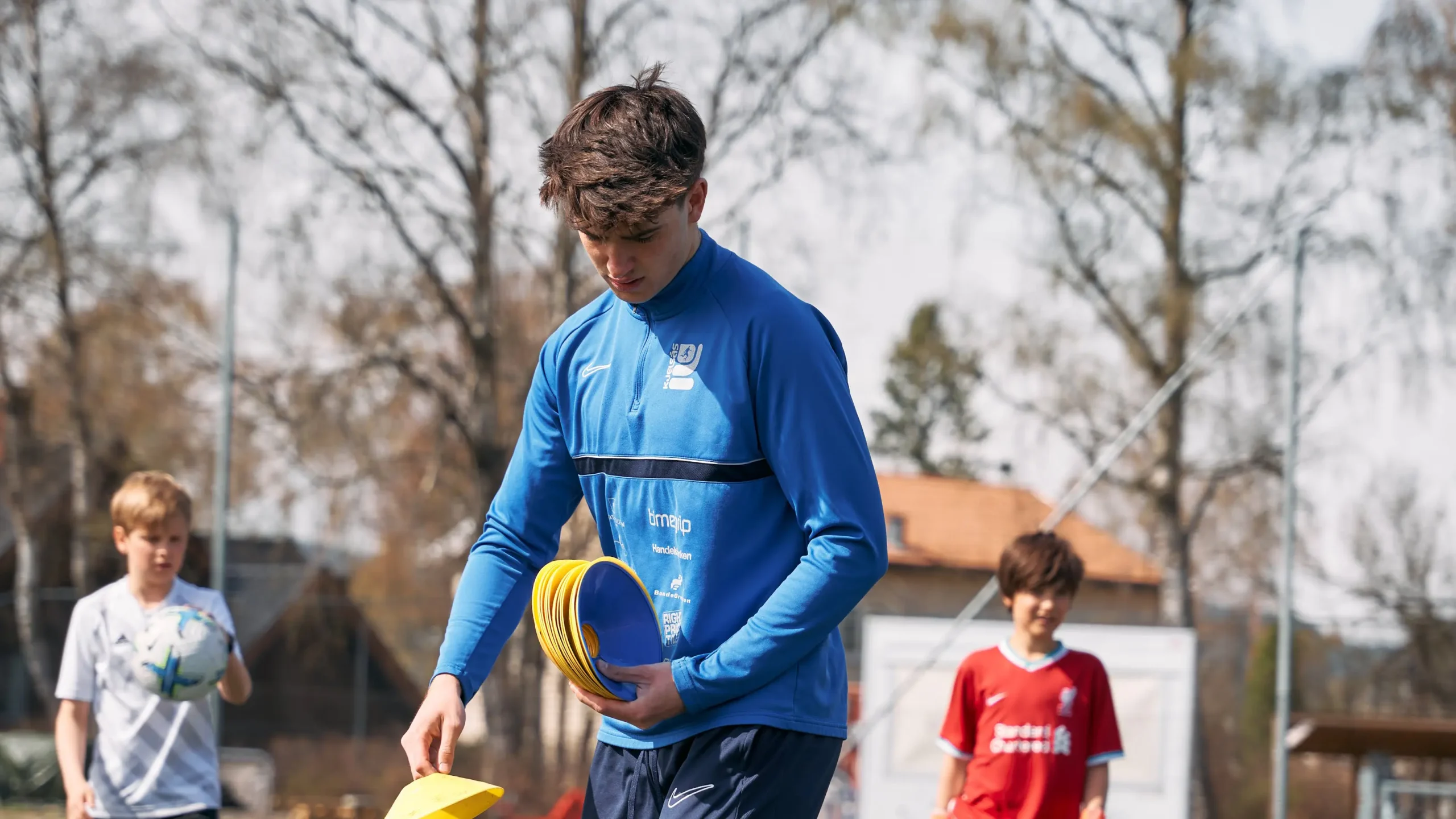 bilde av en fotballtrener som stabler kjegler til trening