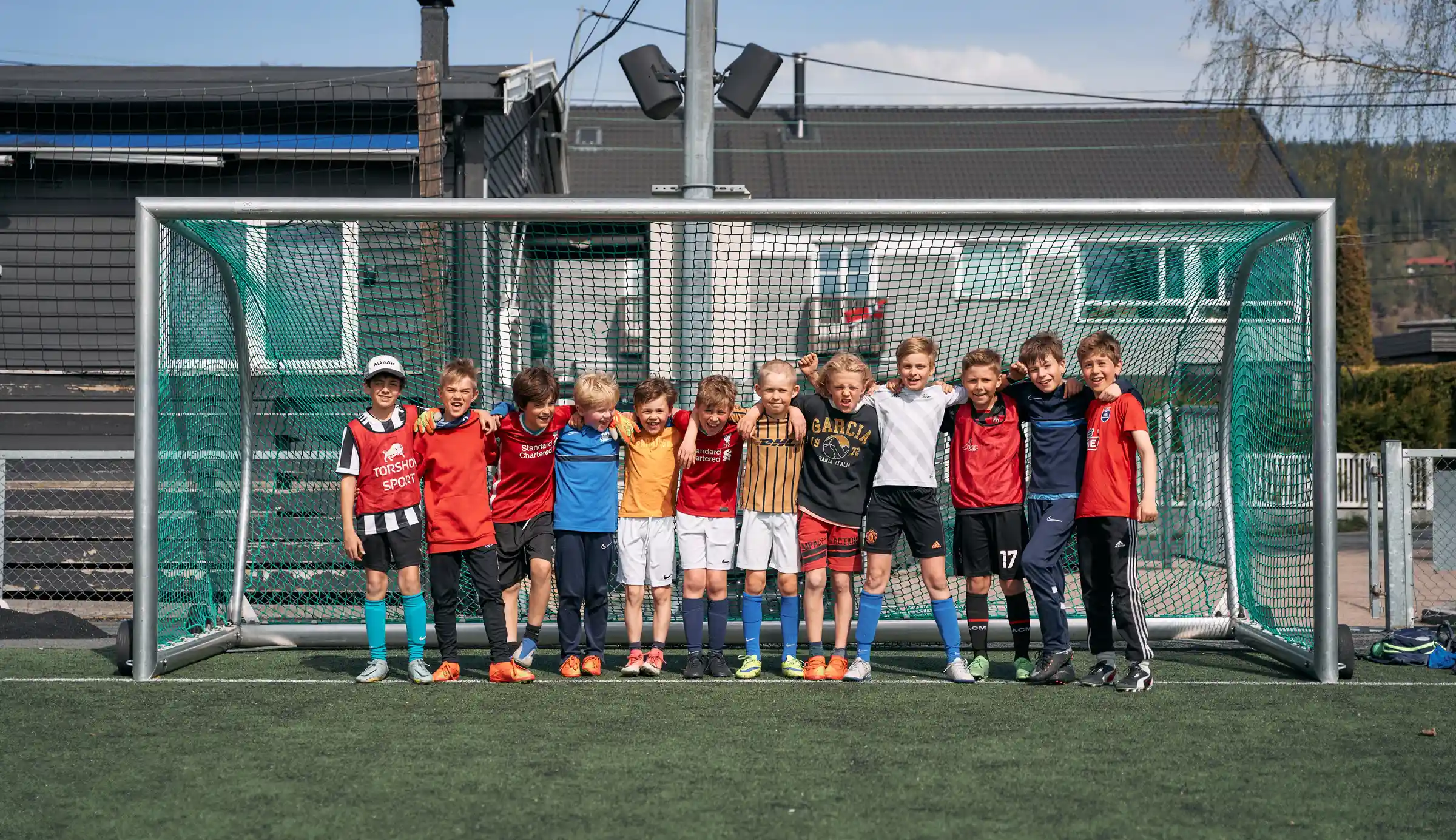 Bildet av barn med ulike fotballdrakter som står sammen for et fotballmål