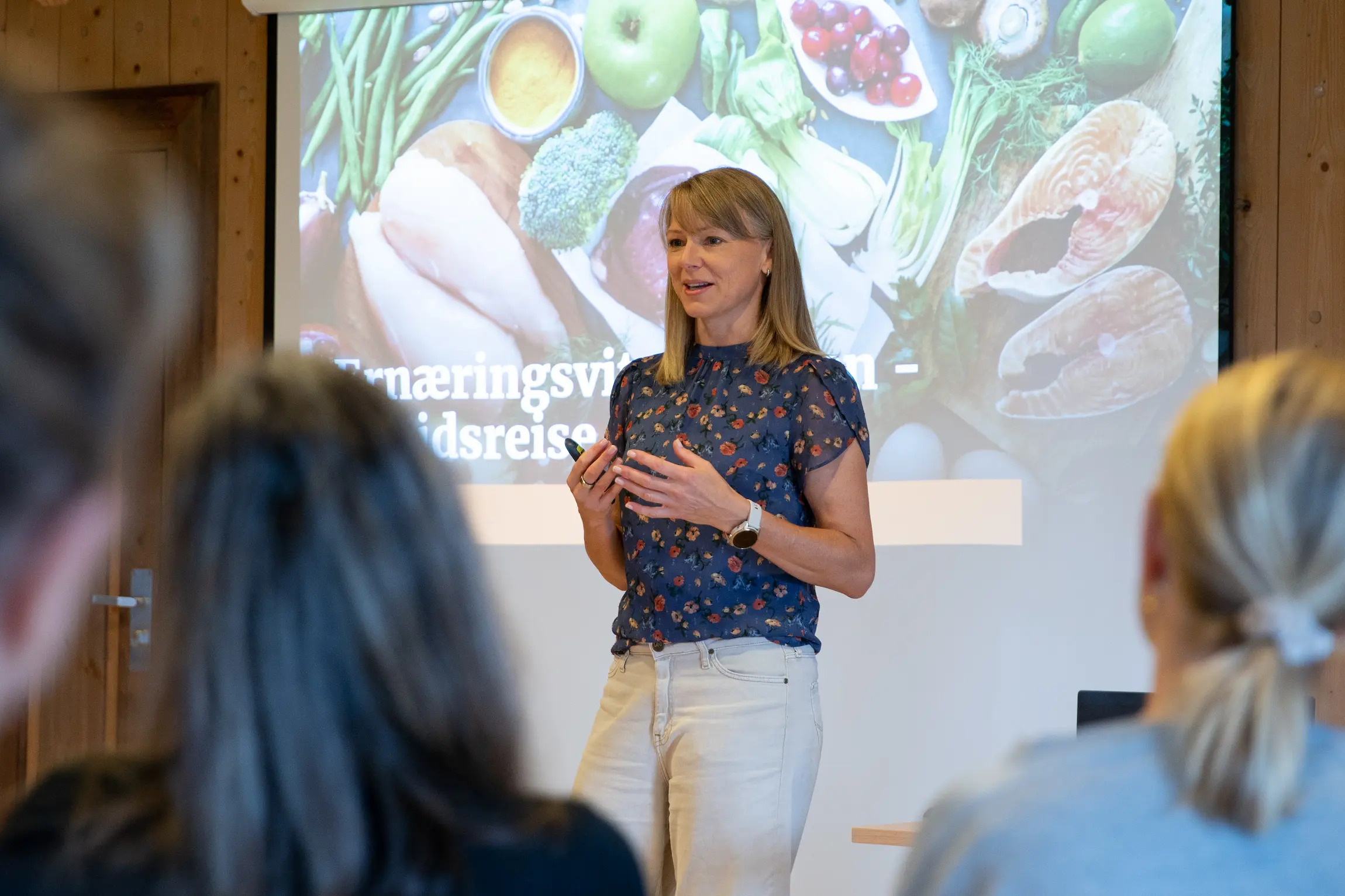 Marit Kolby står foran en stor skjerm og holder et foredrag om ernæring