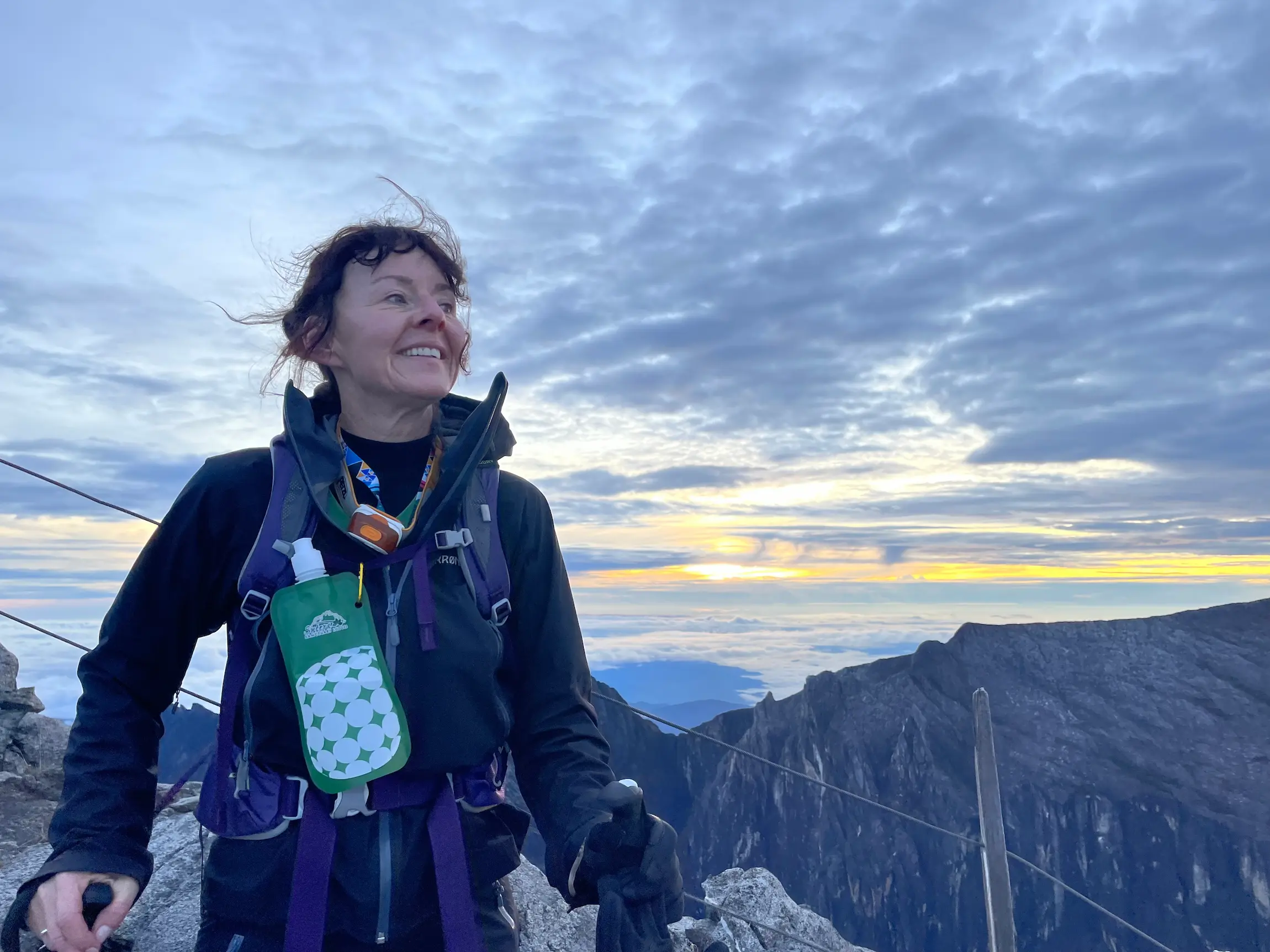 Ragnhild bang nes ivrig på en fjelltur med staver. ser fin himmel i bakgrunnen. 