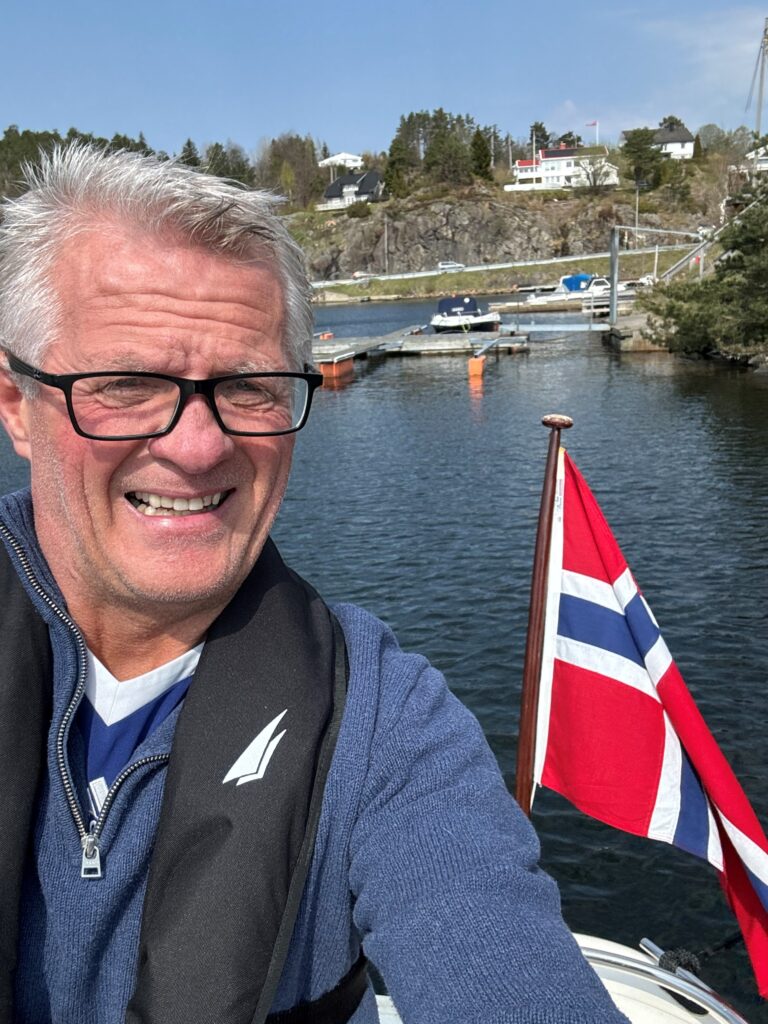 Stig Johnsen smilende på båten en solskinnsdag.