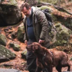 Mann går i skogen og lufter hunden sin.