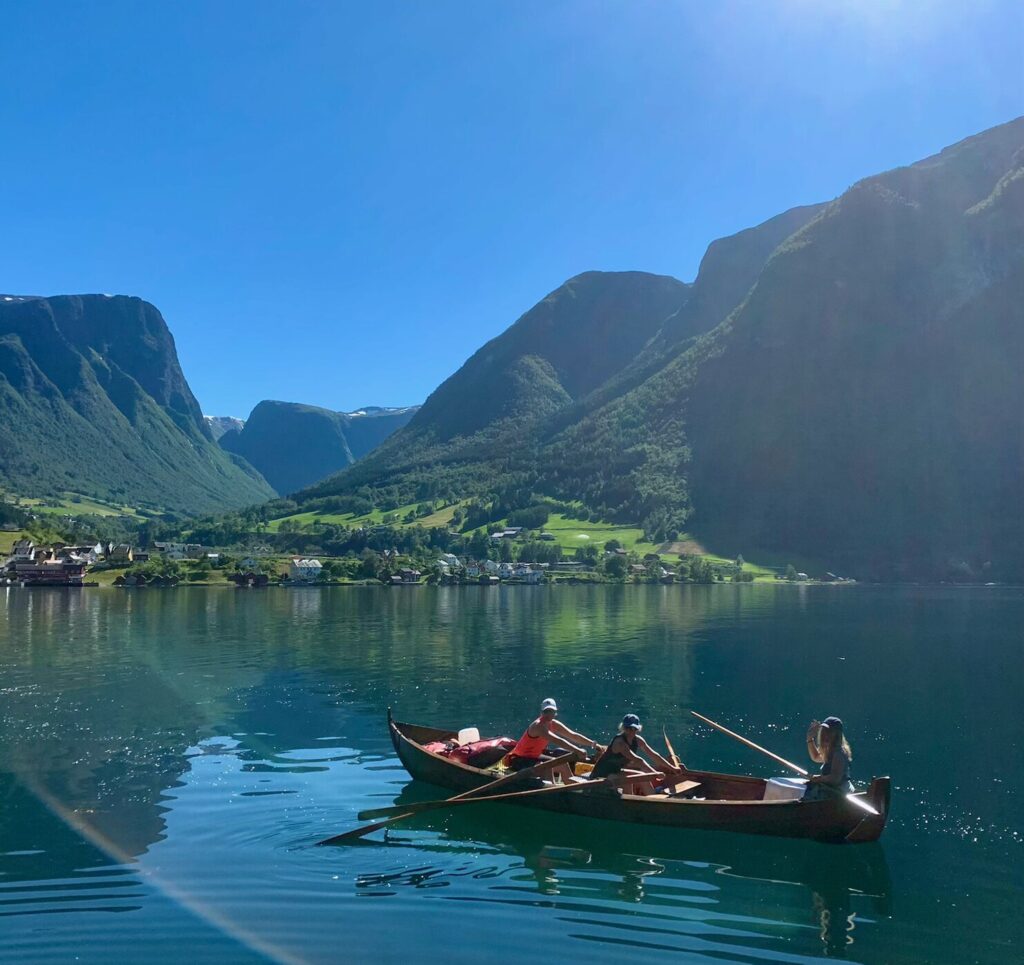 Robåt på fjorden med fjell rundt