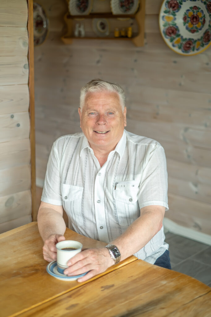 David Eriksen drikker en kaffekopp ved bordet på hytta.