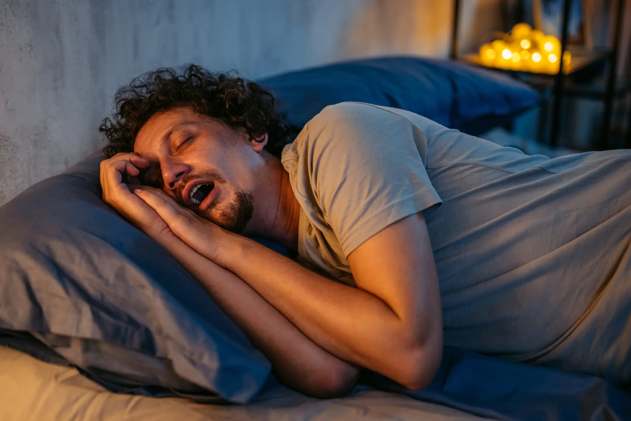 Man lying in bed sleeping with open mouth