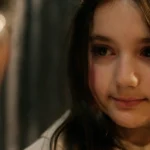 Nærpotrett av 10 år gamle Ronja i filmen Stargate. Hun har på seg Luciakostyme og har blikkontakt med et barn i forgrunnen av bildet.