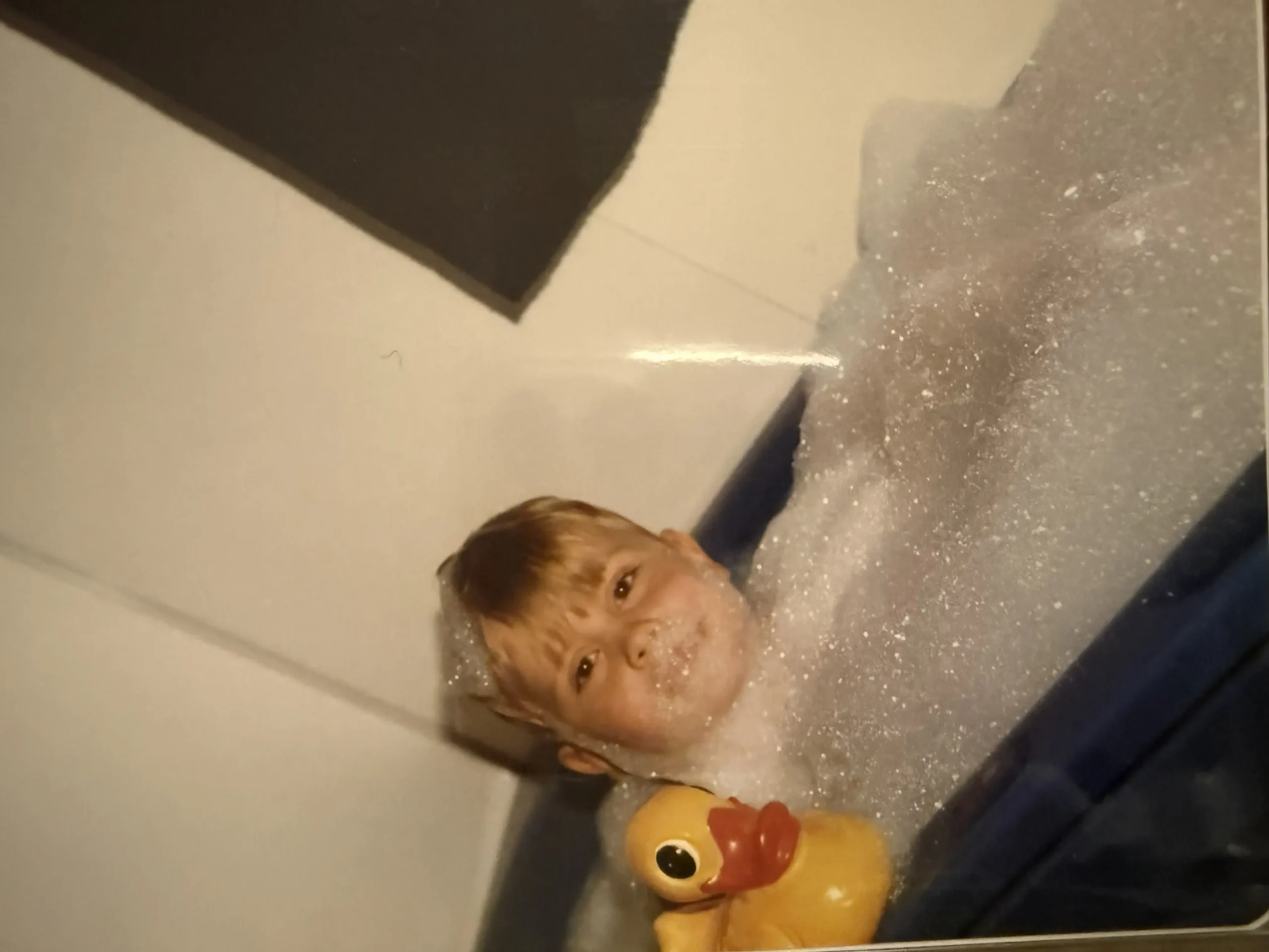 Barnebilde av Ole Erevik. Han er i et badekar med masse skum og holder i en badeand.