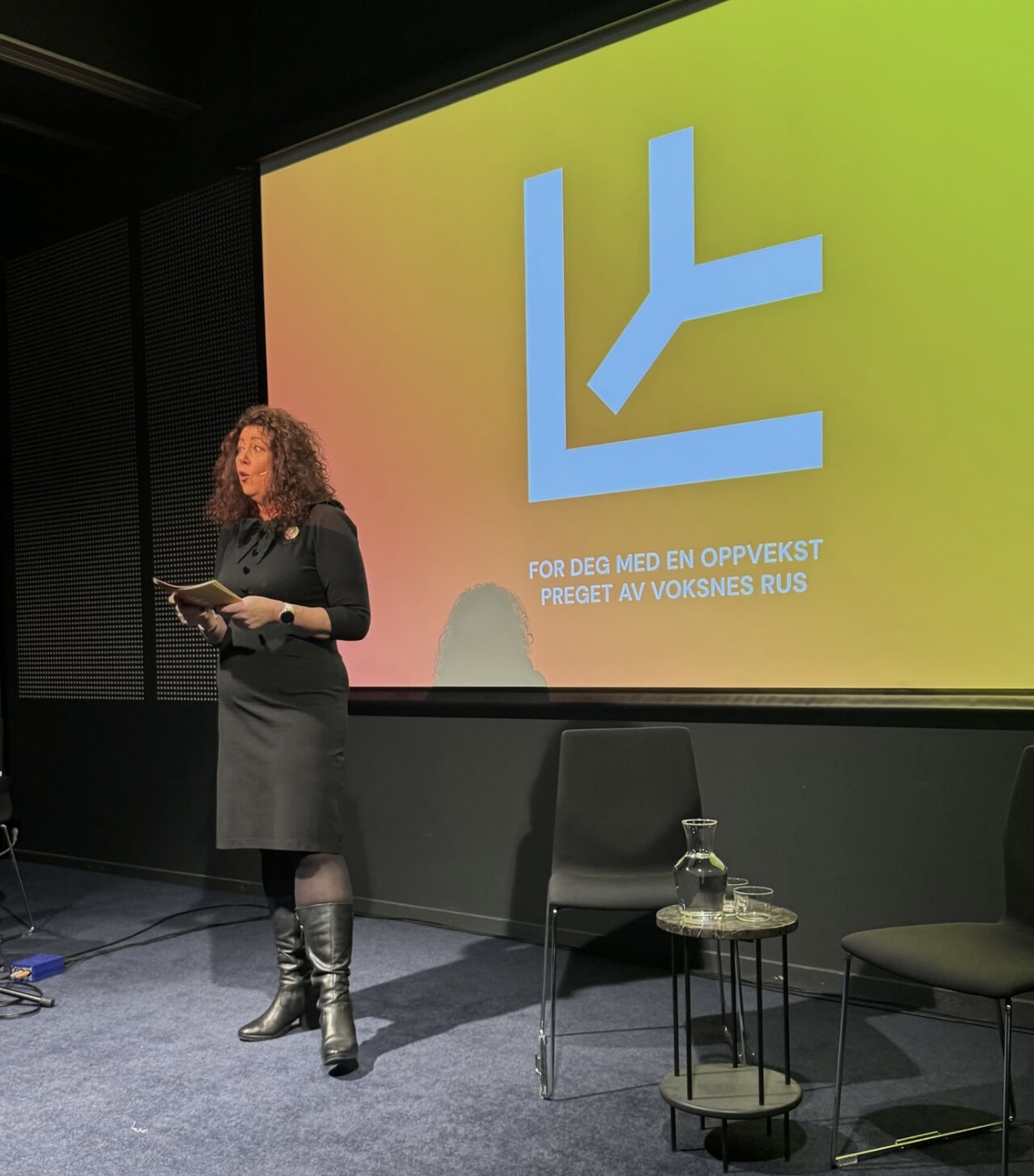 Kristin står på en scene og prater med Ly logoen bak seg.