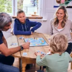 En familie på fire sitter rundt et bord og spiller brettspill.