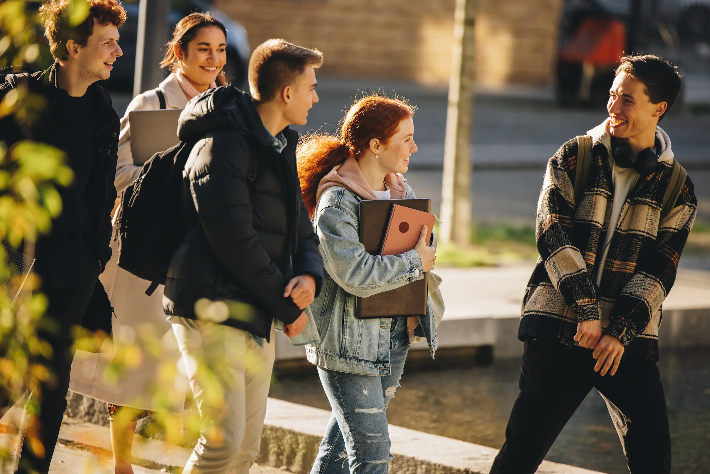 fire unge voksne med skolesekk som prater sammen og smiler