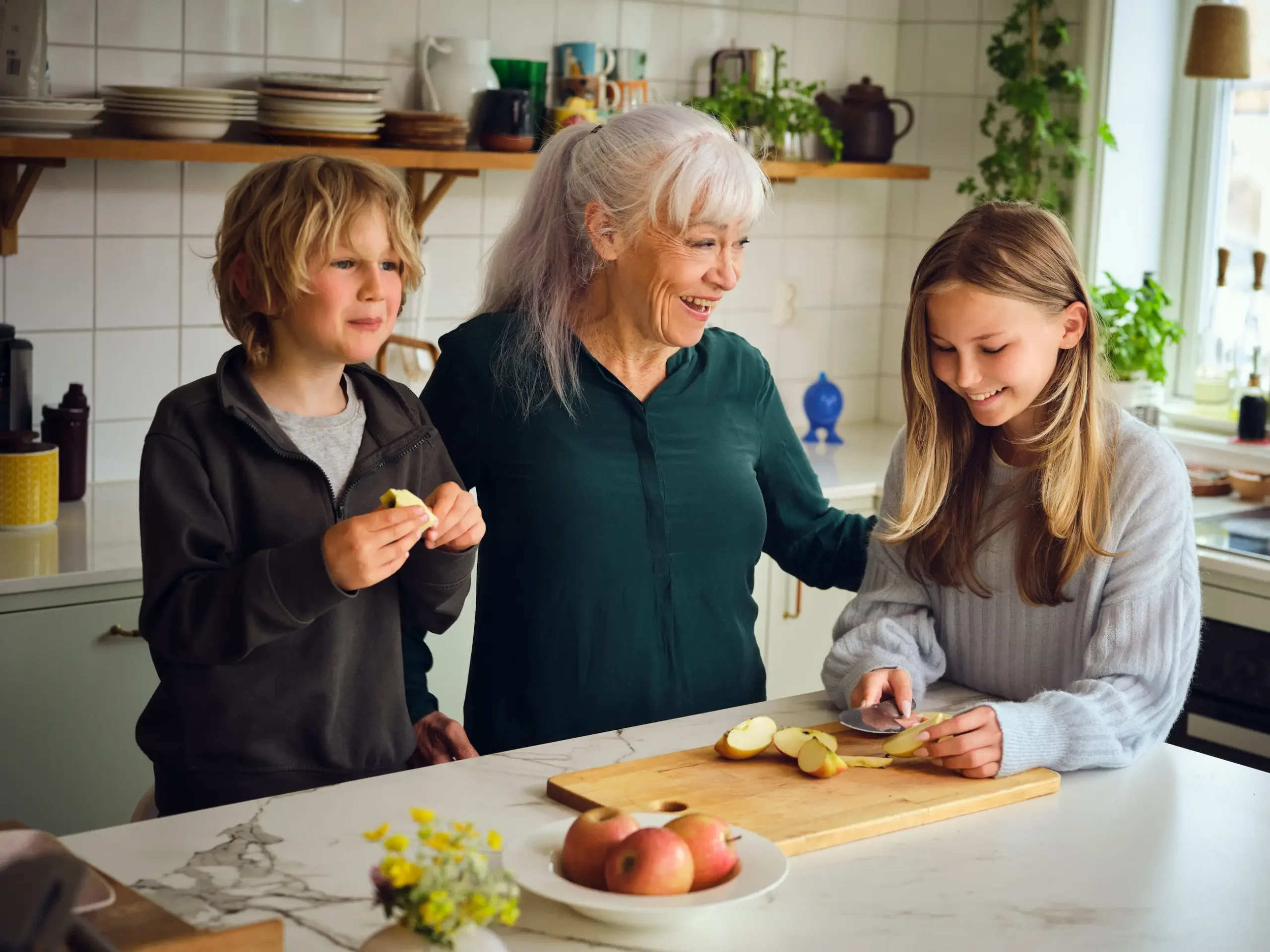 Bestemor på kjøkkenet med to barnebarn.