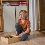 Gutt på omtrent 8 år sitter på gulvet med et spill. Han titter ut i rommet med et tenksomt blikk.