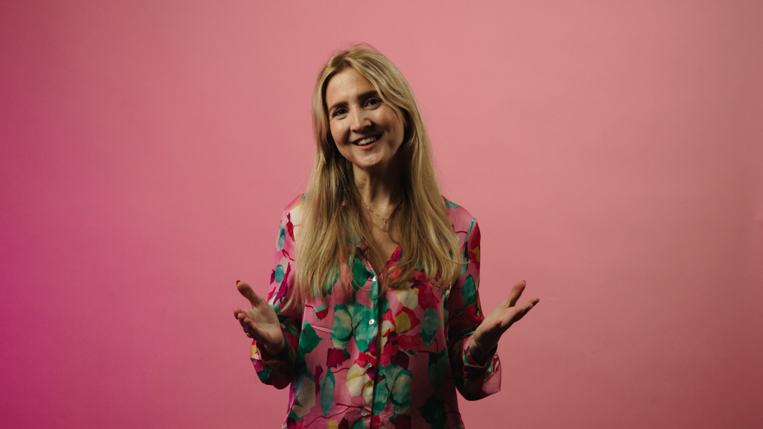 Bilde av Nora, programleder for undervisningsopplegget på en rosa bakgrunn.