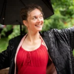 Portrett av psykolog og sexolog Elisabeth Tverrli som står under en paraply og ser smilende til siden.