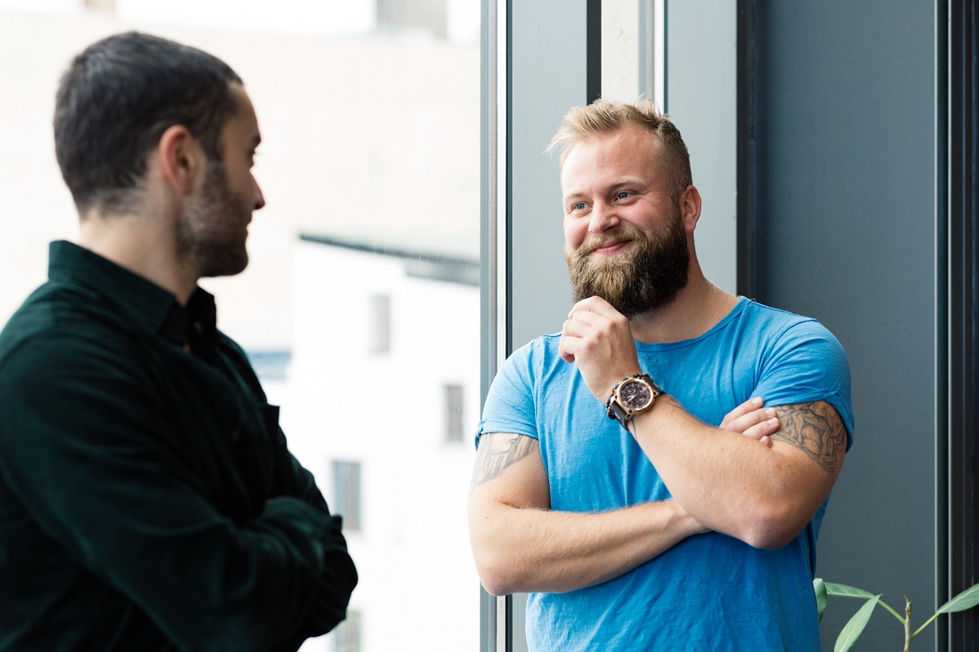 Bilde av to mannlige kolleger som smiler til hverandre under samtale