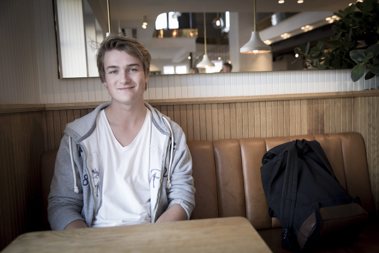 En ung mann sitter på cafe og ser inn i kamera