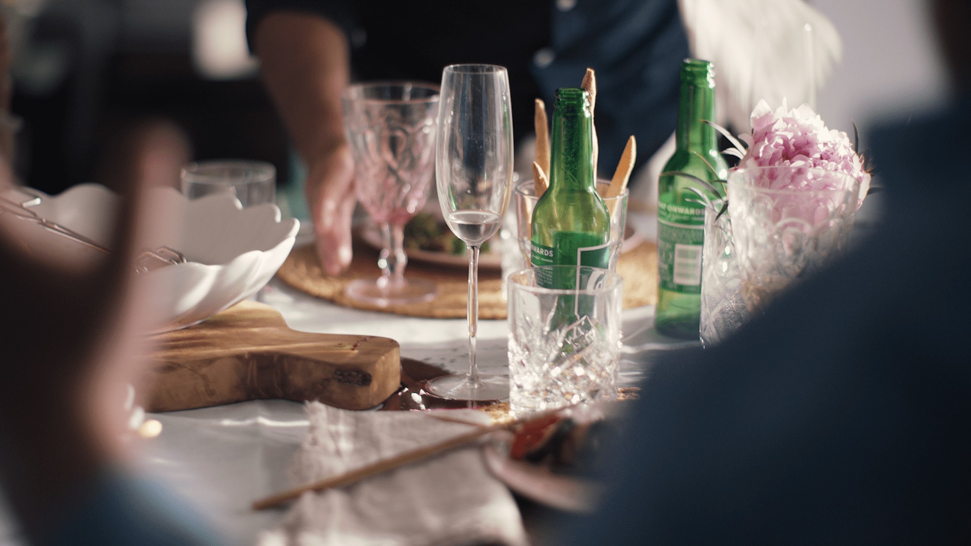 Et detaljbilde fra et middagsbord, med to tomme ølflasker og mange tomme glass