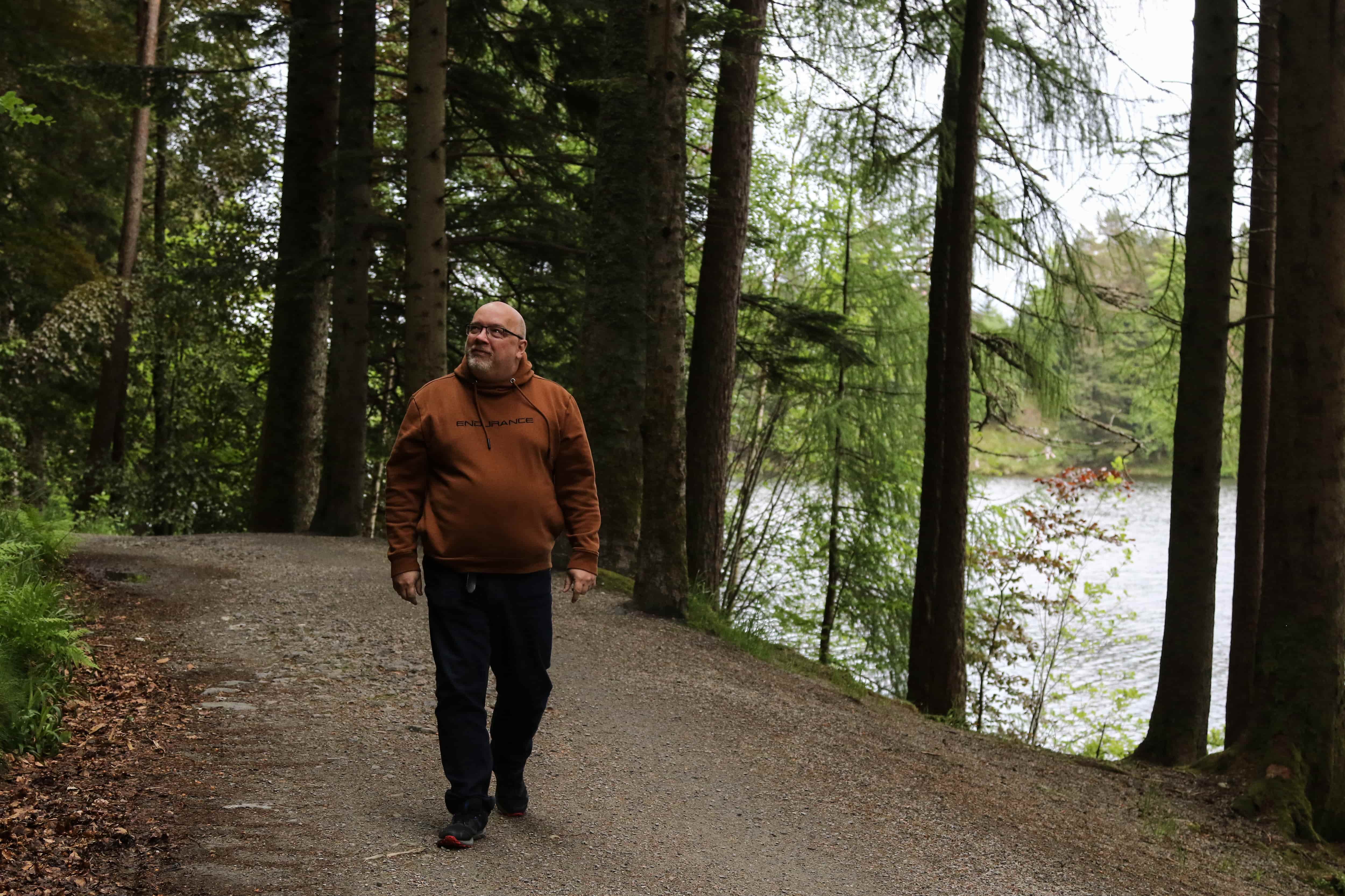 Arne går på en sti i skogen. Foto.