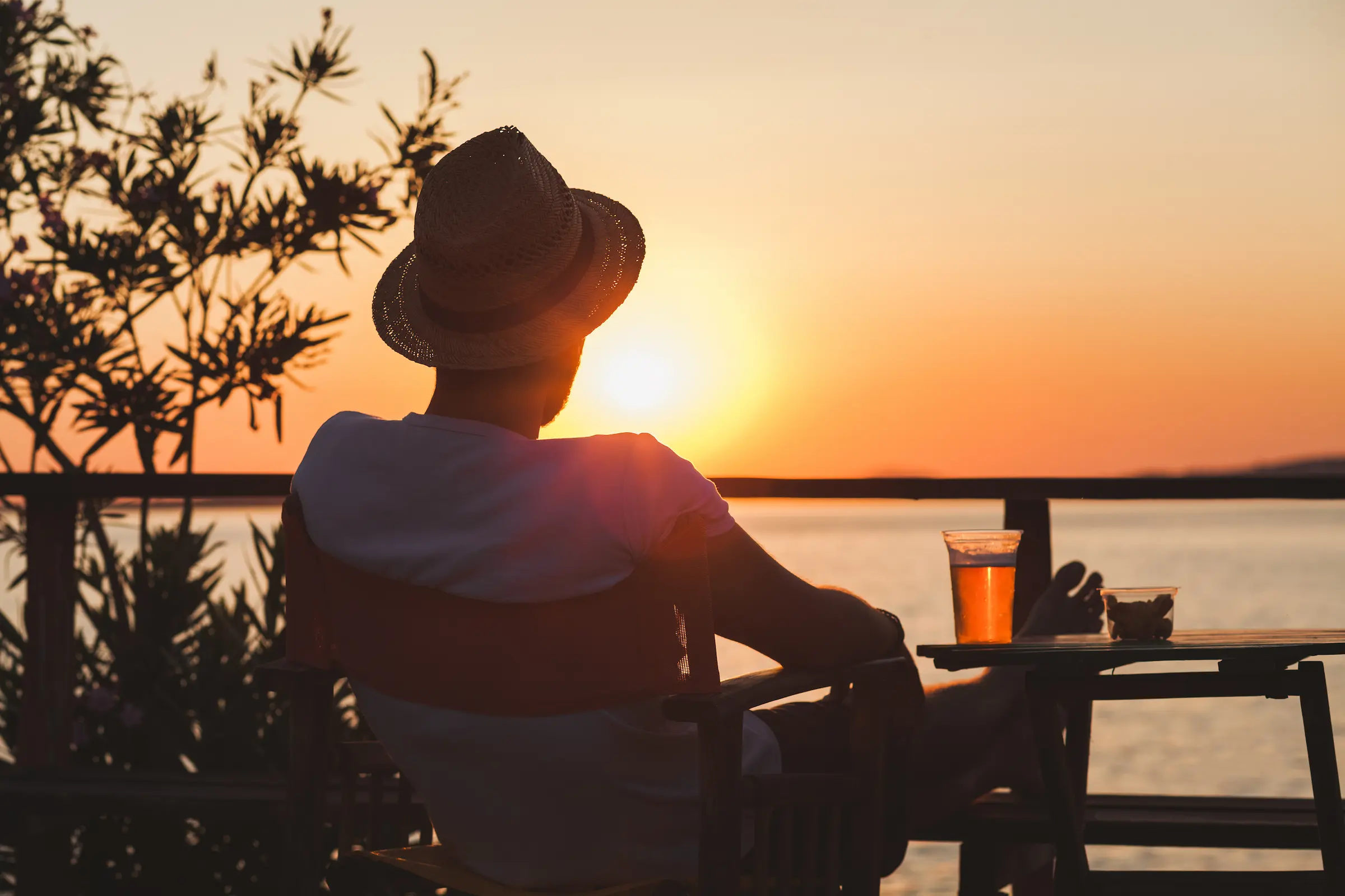 man i solnedgang sitter med en øl foran seg.