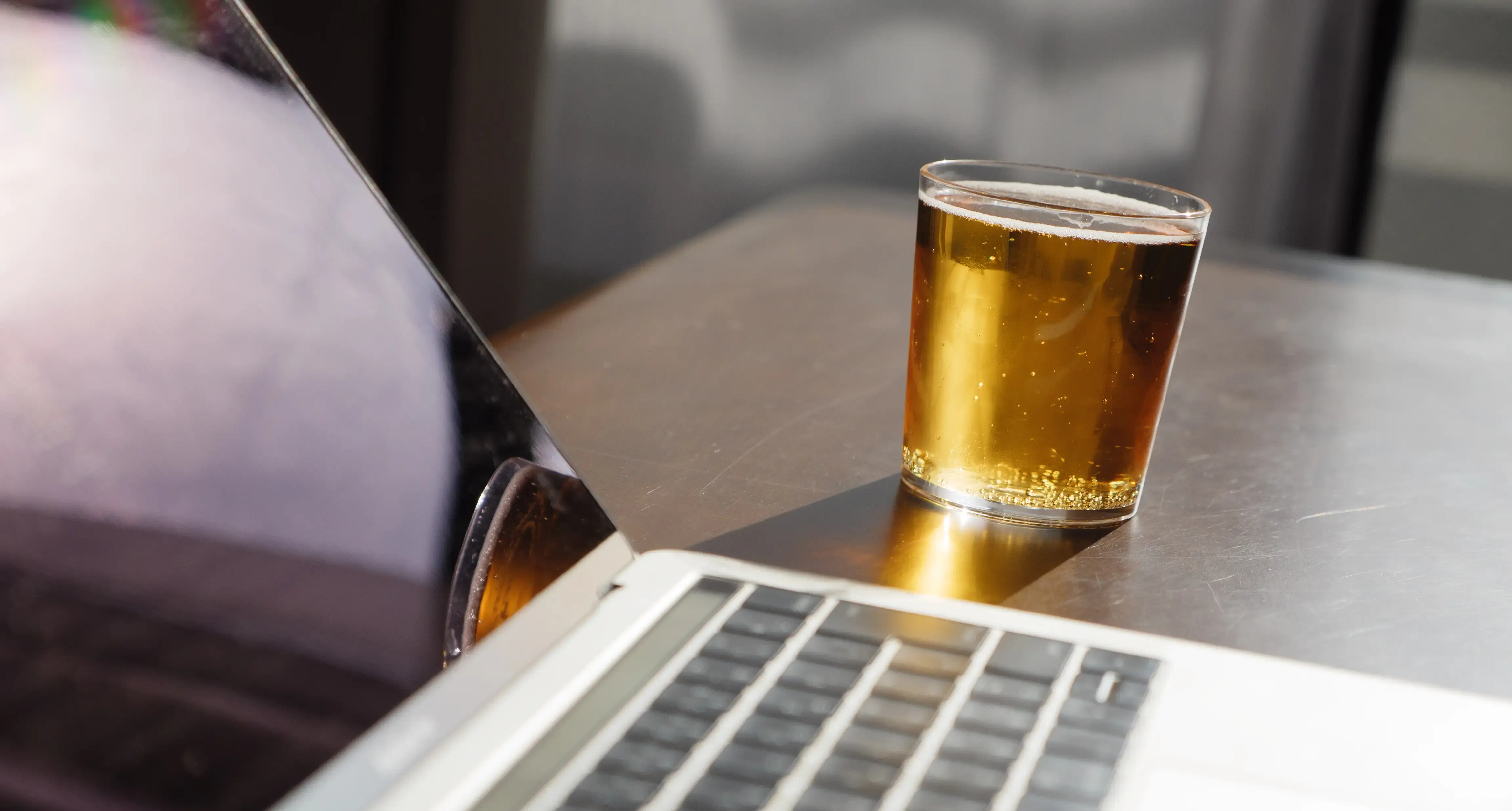 Et glass med øl ved siden av en laptop