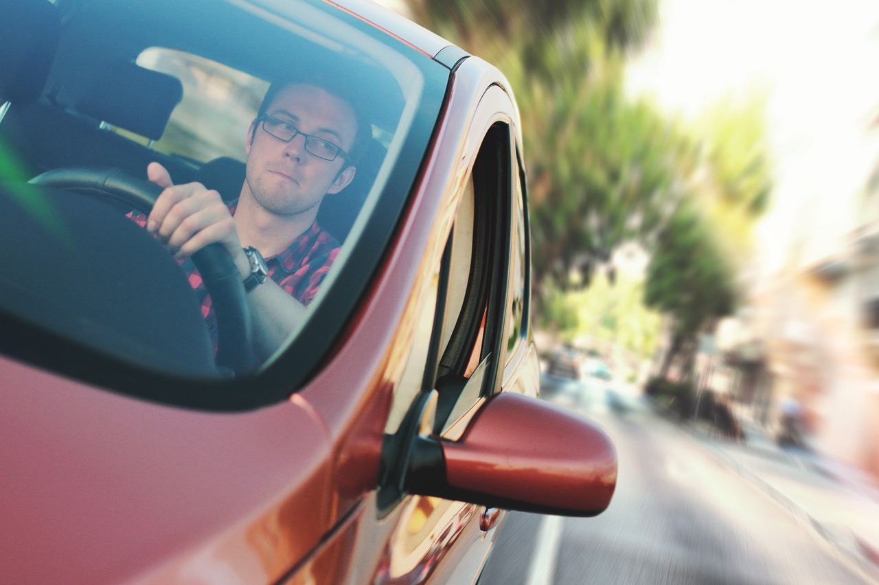 Bilde av en mannlig sjåfør som sitter bak rattet på en rød bil