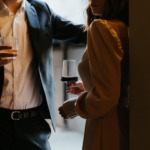 Nærbilde av en mann og en kvinne som snakker med hverandre, og som holder hvert sitt glass med alkohol.