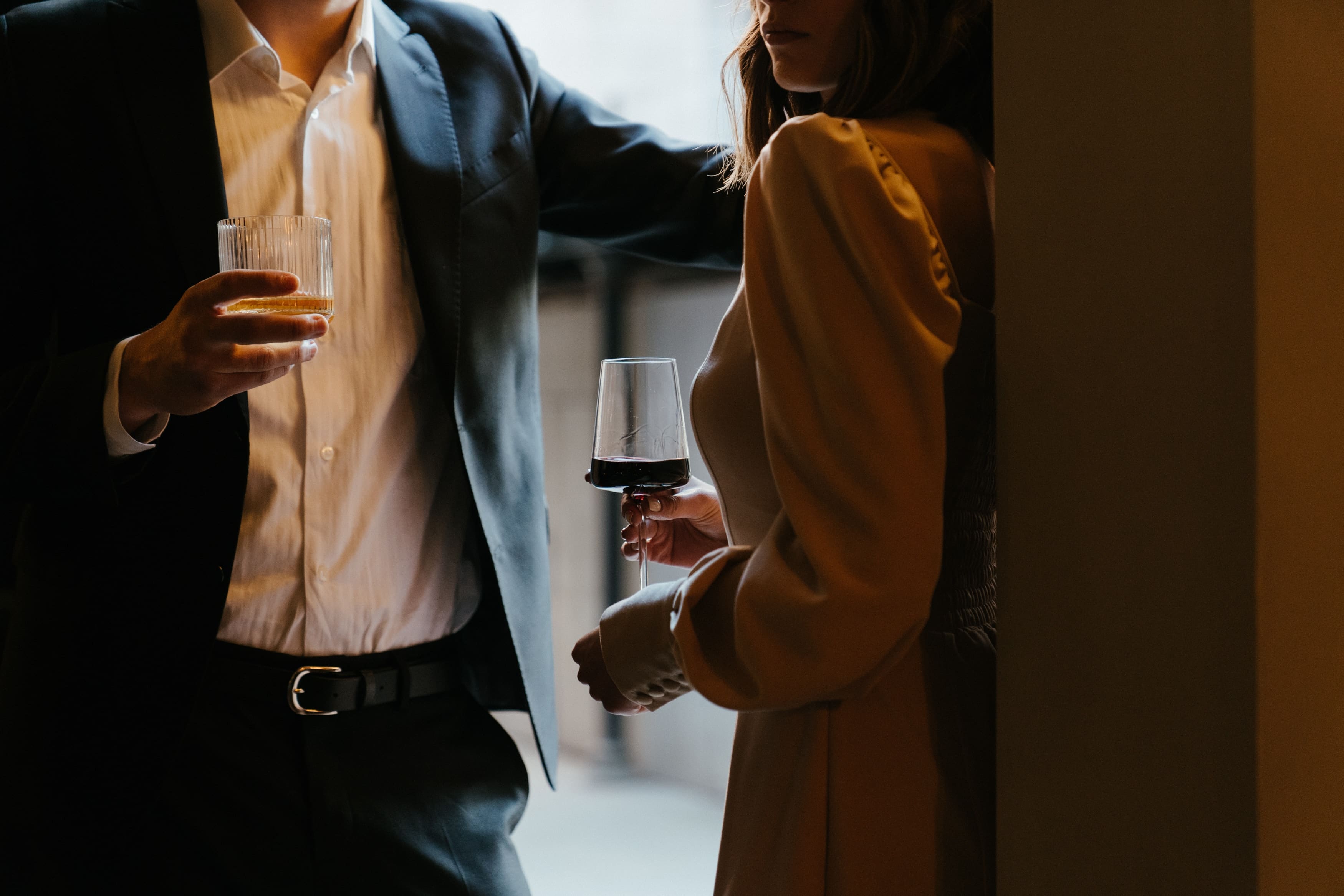 Nærbilde av en mann og en kvinne som snakker med hverandre, og som holder hvert sitt glass med alkohol.