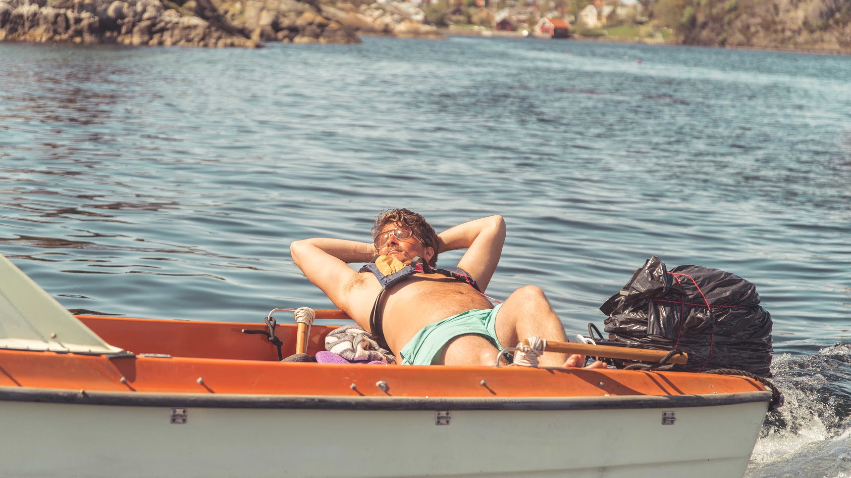 Bilde av kapteinen Jo, som slapper av i sola på tvers i en liten motorbåt.