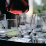 Detaljbilde av tomme glass på et bord. Fokus på stett til et glass, som har inneholder noe rød væske.