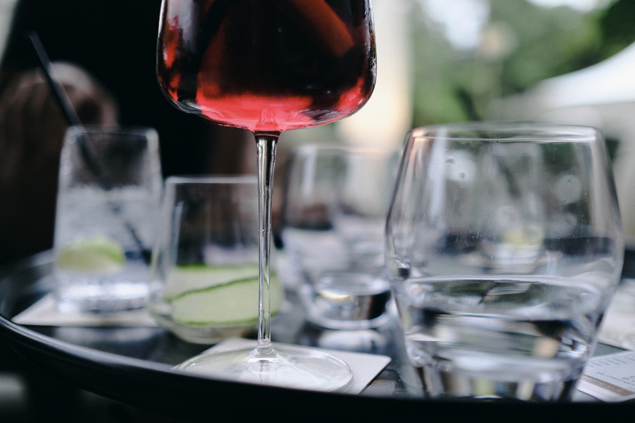 Detaljbilde av tomme glass på et bord. Fokus på stett til et glass, som har inneholder noe rød væske.