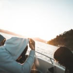 Bilde av tre ungdommer i båt i solnedgang