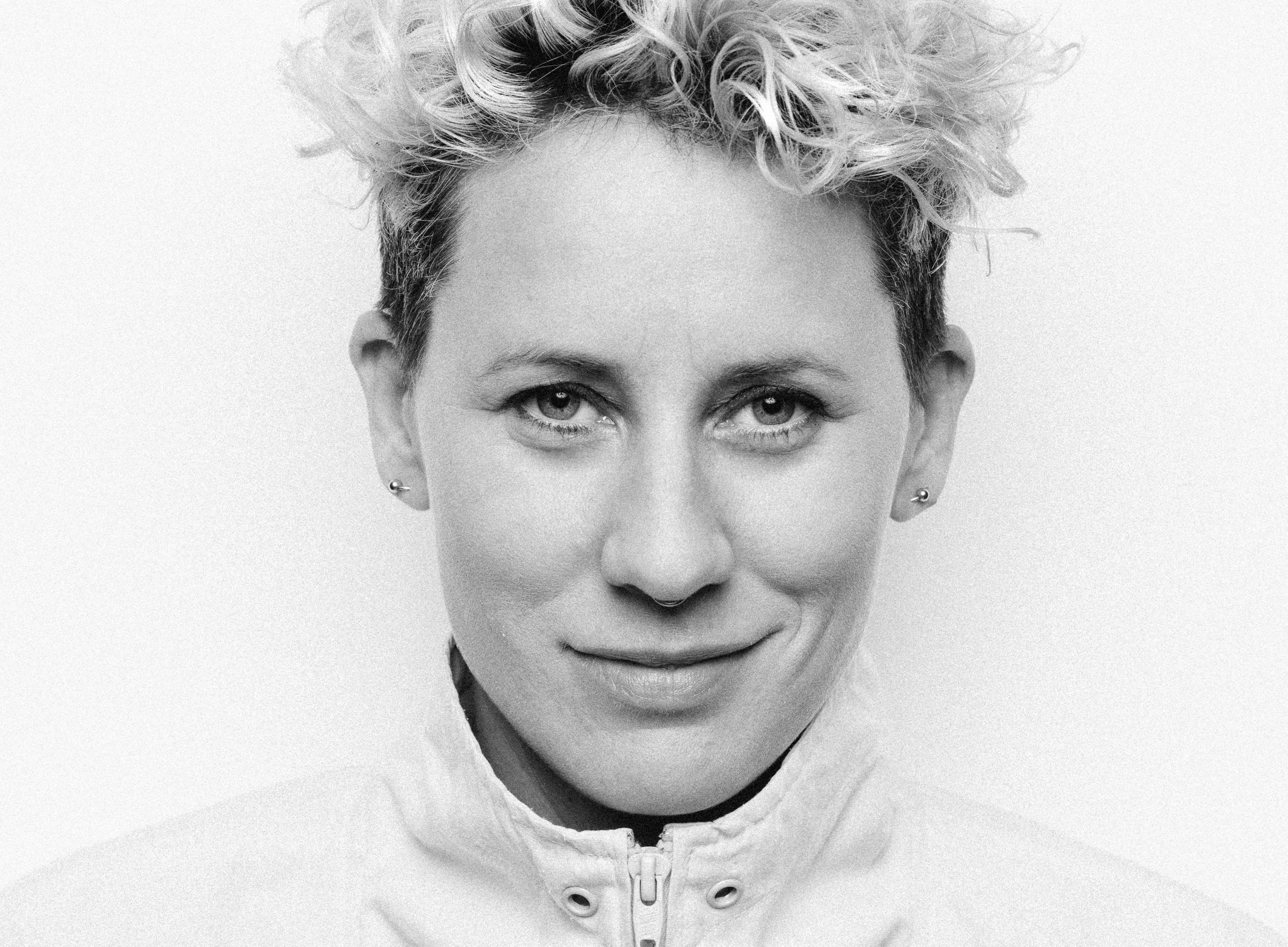 Svarthvitt portrettbilde av Heidi Marie Vestrheim. Hun ser rett inn i kamera med et lurt smil.