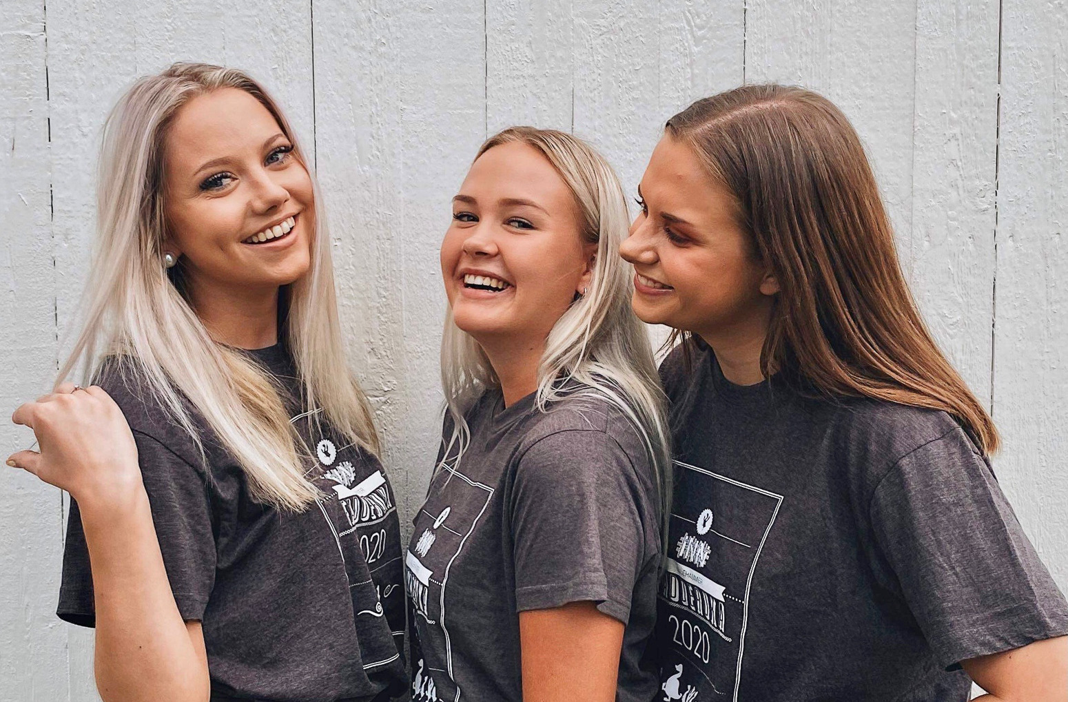 Tre blide venninner ikledd svarte t-skjorter. To ser inn i kamera og ei har blikket rettet mot de to andre.