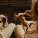 Et ektepar sitter foran peisen med et glass rødvin