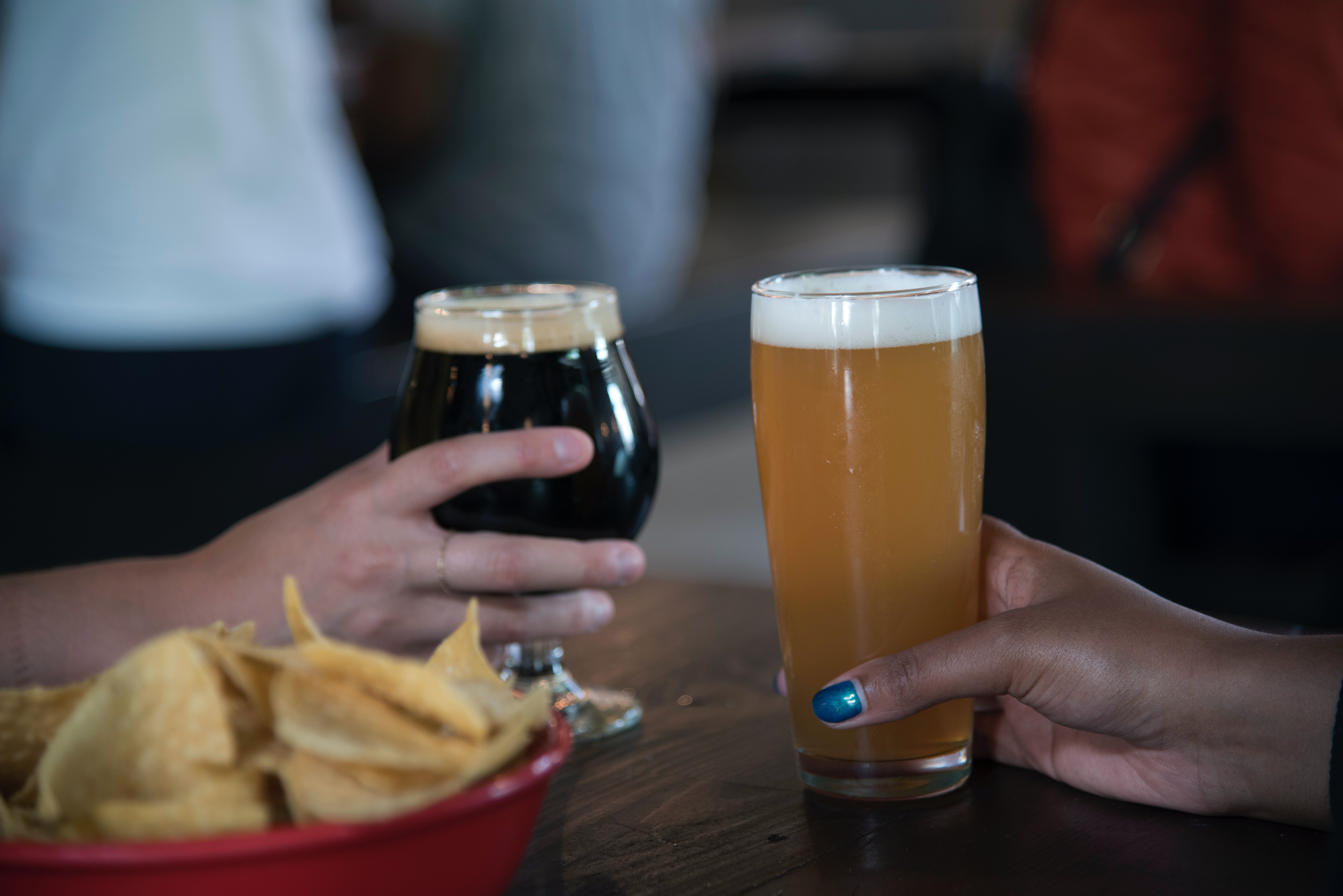 To glass øl står på et bord. En mørk øl og en lys øl. Det er også litt chips i forgrunnen.