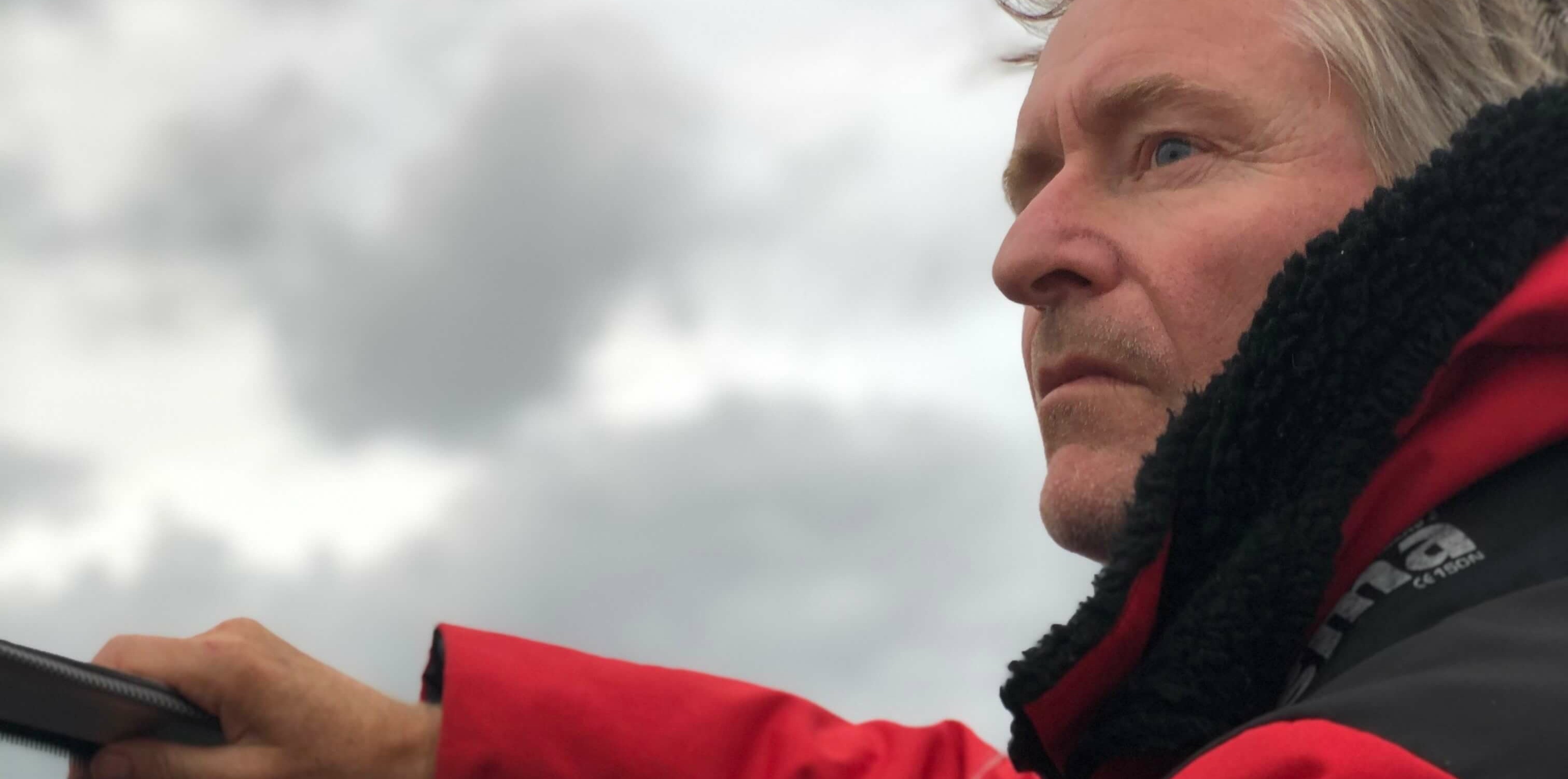 Skuespiller Henrik Mestad står til rors i en båt. Han har på seg en rød kjeledress og ser utover horisonten